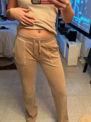 Juicy Couture byxor  - Snygga beige byxor ifrån Juicy Couture med fickor på rumpan. Byxorna har två stora fickor fram och en bakficka med knapp. Sköna och avslappnade med raka ben, perfekta för chill dagar. Mjukt material som känns lyxigt mot huden.✨✨