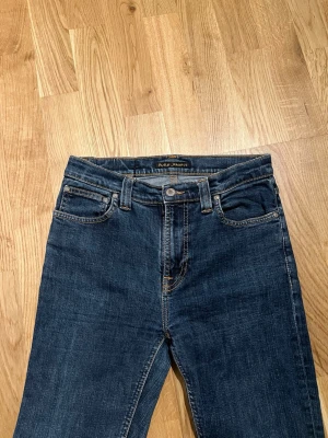 Blå Nudie Jeans  - Nudie Jeans, modell High Kai, i perfekt nyskick. Storlek W30/L32. Ett ikoniskt plagg som lyfter din stil, Missa inte chansen! Hör av dig vid intresse/frågor. PRIS KAN DISKUTERAS!