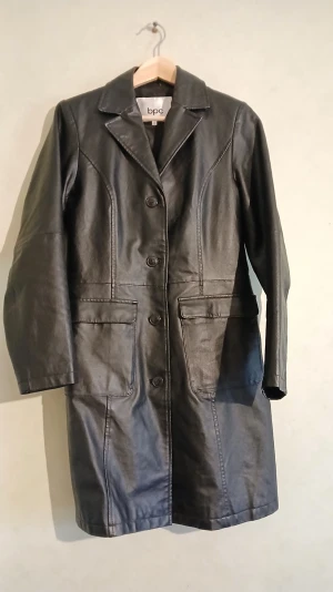 Klassisk svart läderkappa  - Klassisk svart kappa i äkta läder. Jag köpte fel storlek så denna har bara hängt i garderoben. Två innerfickor, varav den ena enkelt rymmer mobilen.