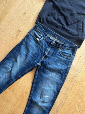 Snygga Nudie Lean Dean jeans - Säljer dessa rejält snygga Nudie jeans 🙌   Storlek: W32 L34 Skick: 9/10 🔥 Riktigt snygga, har några hål på ena knät som är riktigt feta. Modellen Lean Dean, dark deep worn.   💬Skriv vid frågor! 💸 Pris kan diskuteras vid snabb affär! 📦 Skickas snabbt!