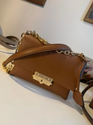 Brun hamilton från Michael Kors - Snygg brun mini hamilton handväska från Michael Kors med guldfärgad kedjerem och elegant metallspänne framtill. Helt ny💓