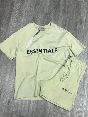 Essentials ljusbeige shorts - Säljer ett par ljusbeige shorts från Essentials med snörning i midjan och logga tryckt på benet. Shortsen har en avslappnad passform och är tillverkade i mjuk bomull, perfekta för sommardagar.