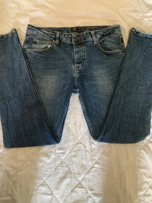 Blå jeans från BOSS - Snygga blå jeans från BOSS med klassisk femficksdesign och raka ben. Jeansen har en lätt tvättad look och är tillverkade i denim med subtila slitningar. Perfekta för en avslappnad och stilren outfit.