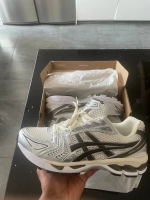 Vita ASICS sneakers med svarta detaljer - ASICS Gel-Kayano 14 Cream Black Metallic Plum  Nya sneakers i riktigt fin colorway, funkar till allt. Sköna och sitter bra på foten.  Finns i storlekar 40–45 