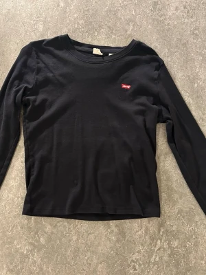 Svart långärmad topp från Levi's - En stilren svart långärmad topp från Levi's med rund halsringning och den klassiska röda Levi's