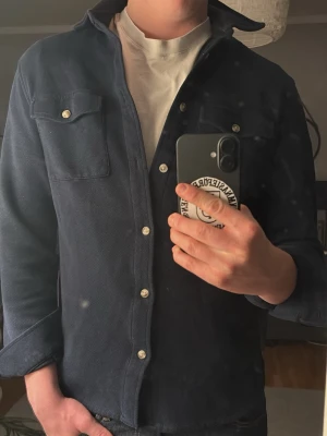Mörkblå overshirt - Säljer en snygg mörkblå overshirt från bondelid. Overshirten har klassisk krage och är tillverkad i ett kraftigare tyg som ger en stilren look. Perfekt att bära över en t-shirt. Hör bara av dig vid någon fråga