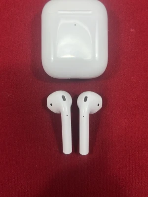 Apple AirPods med laddningsetui - Säljer ett par vita Apple AirPods med laddningsetui. Trådlösa in-ear hörlurar i stilren design, tillverkade i blank plast. Kommer med originalkartong, laddningskabel och manualer. Perfekta för musik, samtal och poddar.