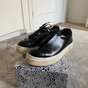 Svarta läder Eytys Doja 40 - Snygga svarta sneakers från Eytys med chunky beige sula och lila detalj på hälen. Väldigt bra skick men begangnade. Säljer pga kommer ej till användning. Storlek 40! Unisex. Följer med tillhörande eytys låda. 