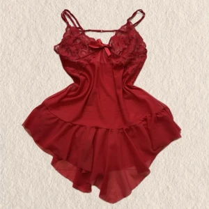 Rött spetsnattlinne med volang - Sött rött nattlinne med tunna axelband, spetsdetaljer upptill och en liten rosett framtill. Djup i ryggen! Kjoldelen har volang och tyget är lätt och något transparent, vilket ger en romantisk känsla. Perfekt för mysiga kvällar hemma.