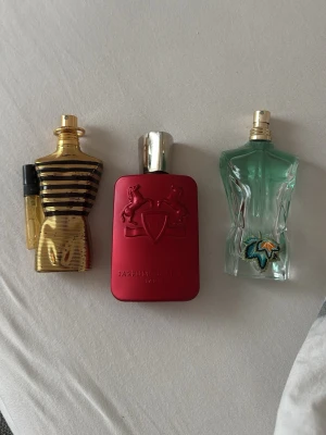 Byter parfym - Tre unika parfymflaskor: en guldig kropp i metall-look från Jean Paul Gaultier, en matt röd rektangulär flaska med silverlock från Parfums de Marly och en turkos kropp med broderad detalj från Jean Paul Gaultier. Snygga och ikoniska designer!