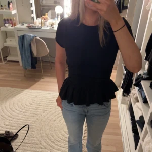 Svart topp med volang - Svart topp med volanger. Helt ny och prislappen kvar!