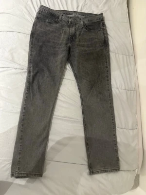 Grå raka jeans från Levi's - Säljer ett par grå jeans från Levi's med rak passform och klassisk femficksdesign. Jeansen är tillverkade i bomull och har Water<LESS>-teknologi som sparar vatten vid produktionen. Perfekta för en avslappnad och stilren look.