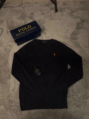  Polo Ralph Lauren tröja - Snygg mörkblå stickad tröja från Polo Ralph Lauren i slim fit-modell.  Den är i mycket bra skick och är i storlek S. Nypris 1995kr vårt pris 499