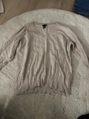 Beige stickad tröja från H&M - Beige finstickad tröja ifrån H&M, tre kvarts ärmar och v ringad, den är lite skrynklig på bilden men de går bort efter en tvätt. Står storlek XL men den passar en M/S ❣️