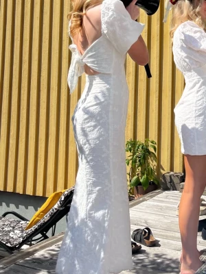 Vit lång klänning från ADOORE  - Superfin lång vit klänning med puffärmar och öppen rygg med knytband från Adoore. Perfekt till tex studenmotagning eller midsommar, eller nu till vår/sommar!  Endast använd 2 gånger 