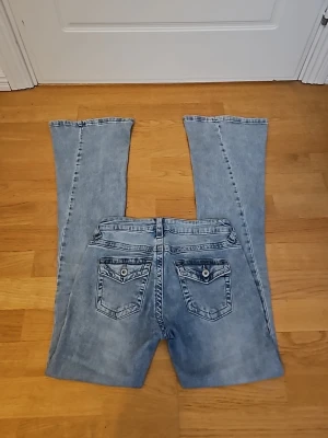 Ljusblå low waist flare jeans från Chelsea i Göteborg  - Säljer ett par ljusblå bootcut jeans från Chelsea i Göteborg och har en jättefina detaljer på bakfickorna. Jeansen är low waist och flare. Storlek W25, 32/34 eller Xs. Pris kan diskuteras 🫶
