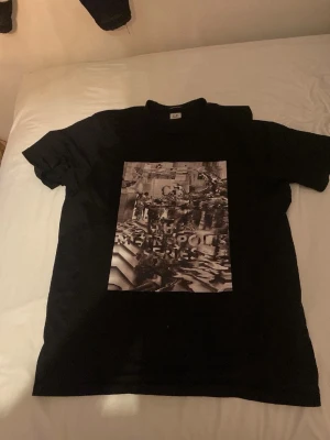 Svart t-shirt med grafiskt tryck - Snygg svart t-shirt med ett stort grafiskt tryck på framsidan där det står 'Metropolis Series'. Klassisk passform och rund hals. Perfekt för dig som gillar streetwear och vill ha en unik look.