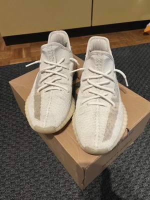 Adidas Yeezy Boost 350 V2 Cream Bone - Säljer ett par Adidas Yeezy Boost 350 V2 i färgen Cream/White. Skorna har en stickad ovandel i Primeknit, genomskinlig sidostrip och en chunky, ribbad sula i vit/gulaktig ton. Klassisk Yeezy-design med snörning och pull tab bak. Perfekta för dig som gillar streetwear. Skulle säga att de passar från 42-43 1/3
