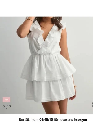 Vit volangklänning med öppen rygg - Supersöt vit kortklänning med volanger, helt oanvänd med prislappen kvar, perfekt till studenten.