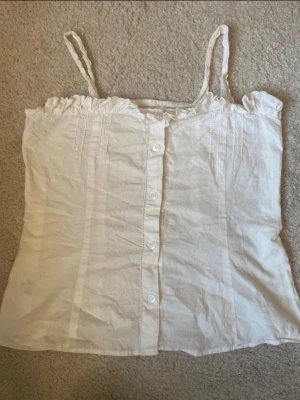 Vit topp - Söt vit topp med smala axelband och knappar. Vet ej märket då jag köpte på vinted🙂(lånad bild)