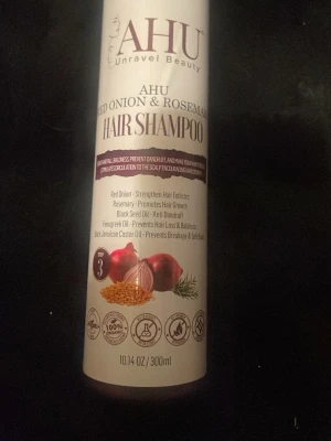 AHU Red Onion & Rosemary Shampoo - Shampoo från AHU Unravel Beauty med röd lök och rosmarin. Innehåller även svartkumminolja, bockhornsklöverolja och jamaicansk ricinolja. Kommer i en vit plastflaska med tryck och rymmer 300 ml. Designen har illustrationer av ingredienserna på framsidan.