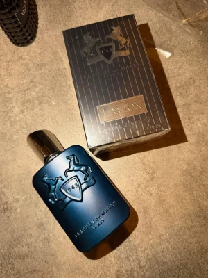 Parfums de Marly Layton EdP 125ml - Exklusiv parfym från Parfums de Marly, Layton Royal Essence. Flaskan är matt mörkblå med silverdetaljer och har ett elegant reliefmönster med två hästar och sköld. Kommer i lyxig svart och guld kartong. Volym: 125 ml. Kvitto finns, nypris 3500kr!