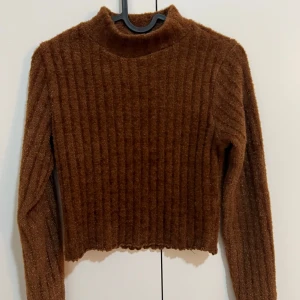 Brun ribbad tröja från Gina Tricot - Säljer en snygg brun ribbad tröja från Gina Tricot. Tröjan är croppad med långa armar 