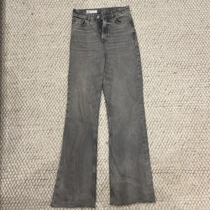 Grå jeans från Zara - Snygga grå jeansbyxor från Zara med hög midja och bootcut. Storlek 34.
