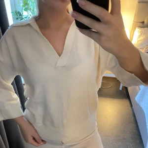 Vit tröja med krage - Säljer en stilren vit tröja med krage och v-ringning. Tröjan har långa ärmar och en avslappnad passform, perfekt för en casual look. Tröjan är lite nopprig vilket jag kan ta bort innan den skickas såklart 