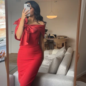 Röd klänning med stor rosett  - Endast använd ett fåtal timmar. Går både att ha över axlar och off-shoulder.