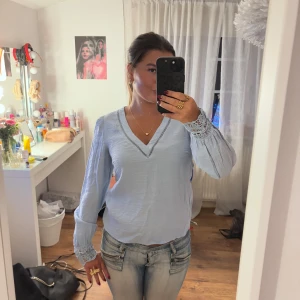 Snygg blå topp - Säljer denna supersöta ljusblå blus med v-ringning och vackra spetsdetaljer vid ärmsluten. Den är i bra skick och säljer pågrund av att den är lite liten på mig och kommer därför inte till användning. Går att använda till vardags och klä upp!💘