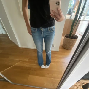 Blå jeans med bootcut - Snygga blå jeans med bootcut-stil och klassisk femficksdesign. Perfekta för en avslappnad look. De har en lågmidjad passform och är tillverkade i jeansmaterial. De är lågmidjade. Midjemåttet är 37 och inrebenslängden är ungefär 80. Lite slitna där nere