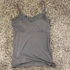 Grå linnetopp med spetsdetaljer - Snygg grå linnetopp med smala axelband och spetsdetaljer vid bysten. 