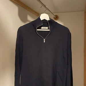 Marin blå  tröja med dragkedja från Jack and Jones  - Snygg marinblå  tröja från Zara med dragkedja i halsen. Perfekt för en stilren look. Tröjan har långa ärmar och en enkel design som passar till det mesta.