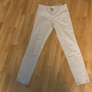 Beige chinos - Snygga beige chinos med normal passform och midwaist. Perfekta för en stilren look. De har en knapp och dragkedja framtill samt fickor både fram och bak. Midja 31 längd 34