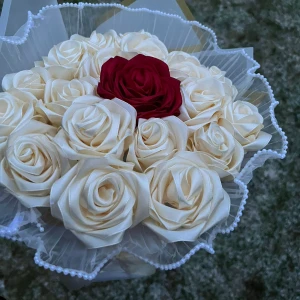 Bukett med vita och en röd ros - Vacker bukett med vita rosor och en iögonfallande röd ros i mitten. Perfekt som dekoration eller gåva. Rosorna är omsorgsfullt arrangerade med ett skirt vitt tyg och pärldetaljer runt om. OBS: beställs minst 10 dagar innan leverans 🚚
