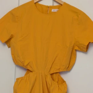 Gul klänning från Zara - Säljer en solgul klänning från Zara i storlek 164. Klänningen har korta ärmar och en rund halsringning. Tillverkad i bomull, vilket gör den bekväm och luftig. Perfekt för varma dagar!