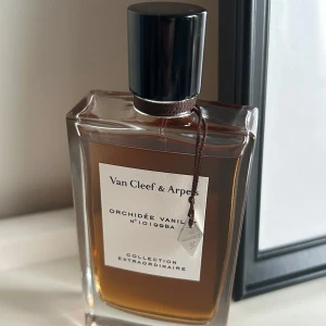 Orchidée Vanille från Van Cleef & Arpels - Elegant parfymflaska från Van Cleef & Arpels, Orchidée Vanille, med en lyxig doft av vanilj. Flaskan är rektangulär med en svart kork och en stilren etikett. Endast testad. 