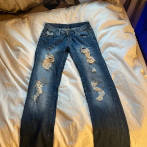 Blå jeans med slitningar  - Snygga blå jeans med slitningar på framsidan och broderade detaljer på bakfickorna. Säljer då jag inte använder dem längre, midjemåttet rakt över är 35cm💕 bootcut/straight, finns ingen lapp med strlk men för mig som har 32/34 i jeans passar perfekt