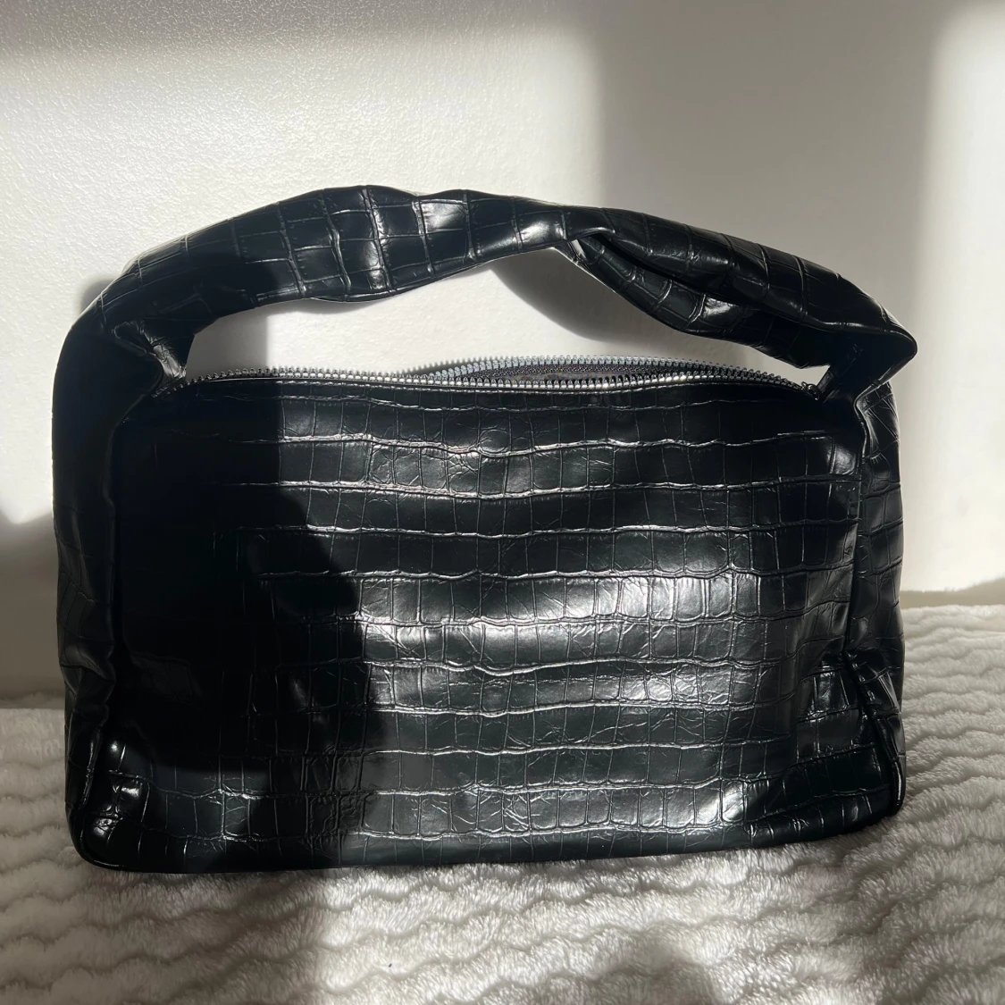 Svart axelväska i syntet med krokodilmönster