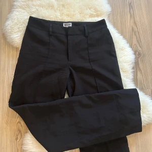 Svarta byxor från Madlady - Snygga svarta byxor från Madlady i en klassisk stil. De har en rak passform och är perfekta för en stilren look. Byxorna har hällor för bälte och en diskret dragkedja framtill.
