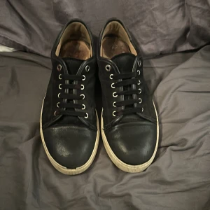 Svarta sneakers från Lanvin utan gläns - Snygga svarta sneakers från Lanvin med klassisk snörning och vit sula. Perfekta för en stilren look.