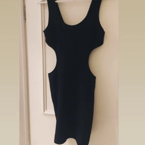 Svart klänning från Bik Bok - Snygg svart klänning från Bik Bok med cut-out detaljer i midjan. Perfekt för en kväll ute eller en speciell tillställning. Klänningen har en tight passform som framhäver figuren.