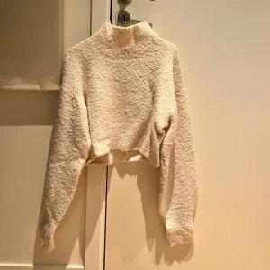 Vit croppad tröja från Monki - Säljer en mysig vit croppad tröja från Monki. Tröjan har en hög krage och är tillverkad i ett bouclétyg. Jättefin!