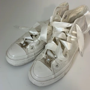 Vita blommiga sneakers från Converse 36.5 - Snygga vita Converse sneakers med blommigt mönster och breda satinband som snörning. Skorna har en klassisk hög modell med Converse-logga på sidan och rosa detaljer på hälen. Köpt som limited edition i Asien 
