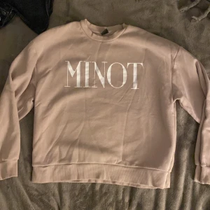 Beige sweatshirt från Gina Tricot - Säljer en beige sweatshirt från Gina Tricot med texten 'MINOT' tryckt på framsidan med vit text. Tröjan har långa ärmar och en rund halsringning. Tröjan är knappast använd. 