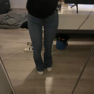 Blå bootcut jeans - Snygga blå bootcut jeans med en klassisk look. De har en tight passform upptill och blir vidare nedtill, vilket ger en skön retrostil. Perfekta för dig som vill ha en avslappnad men ändå stilren look.