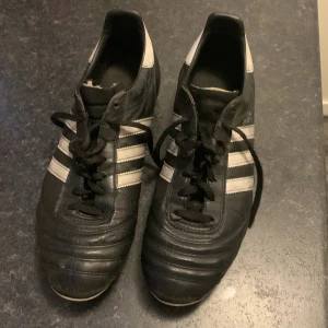 Adidas Copa Mundial fotbollsskor - Säljer ett par klassiska Adidas Copa Mundial fotbollsskor i svart och vitt. Skorna har snörning och är tillverkade i skinn med dobbar för bra grepp på planen.