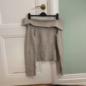 Beige ribbad offshoulder tröja från H&M - Säljer en stilren beige ribbad offshoulder tröja från H&M. Perfekt för en trendig look med långa ärmar och en bekväm passform. Passar utmärkt till både jeans och kjol.