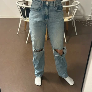 Blå ripped jeans - Snygga blå jeans med slitningar på knäna. De har en hög midja och en straight passform. Perfekta för en avslappnad stil.